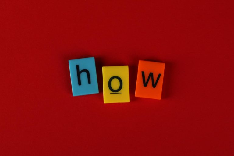 Colorful letter tiles spelling 'How' on a vibrant red background, ideal for educational content.