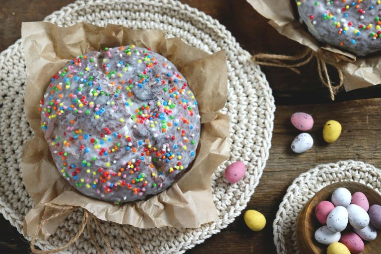 An Easter cake topped with colorful sprinkles, accompanied by mini candy eggs on a rustic table setting.