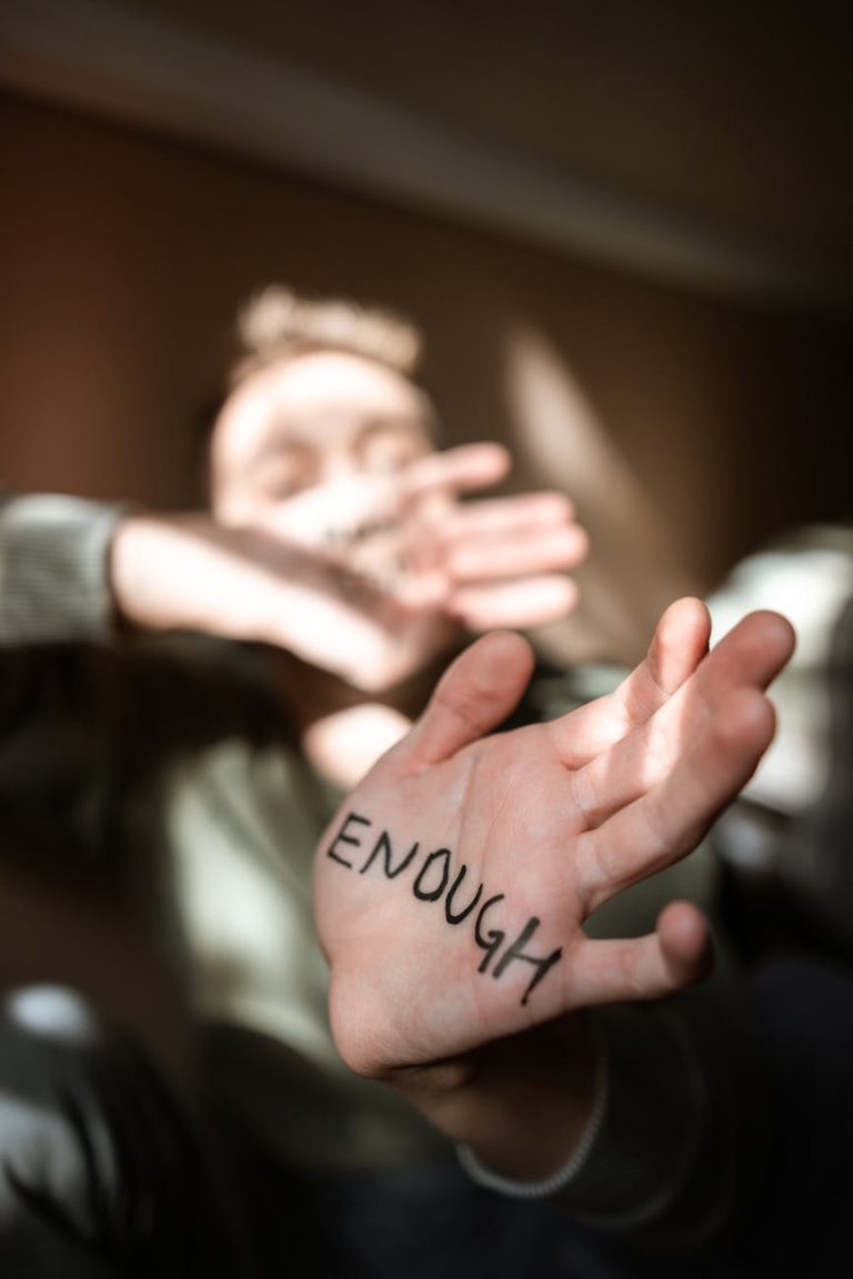 Blurred person with 'Enough' written on palm, expressing empowerment and resilience.